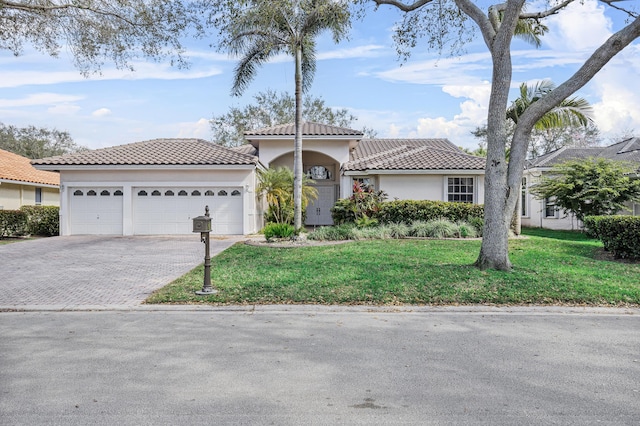 mediterranean / spanish-style home featuring a garage and a front lawn