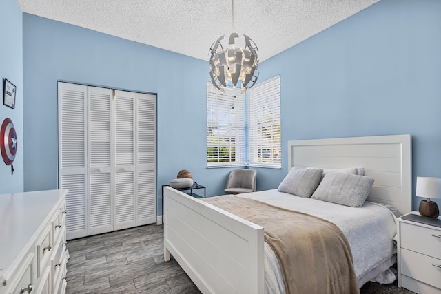 bedroom with hardwood / wood-style floors, a textured ceiling, a chandelier, and a closet