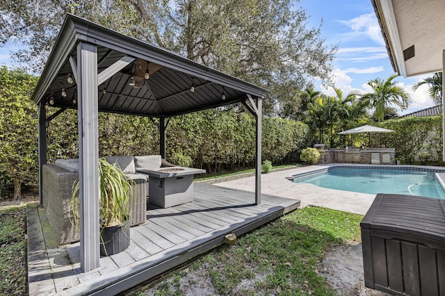 view of swimming pool featuring a wooden deck, a fire pit, and a gazebo