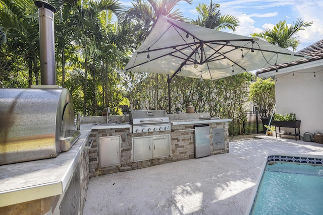 view of patio featuring a fenced in pool, area for grilling, exterior kitchen, and sink