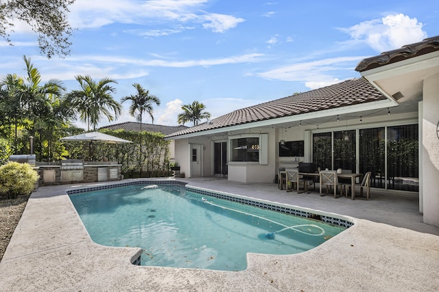 view of pool with area for grilling, exterior kitchen, and a patio