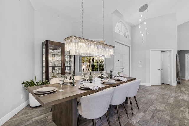 dining area featuring hardwood / wood-style flooring, a chandelier, and high vaulted ceiling