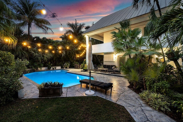 pool at dusk with a patio area