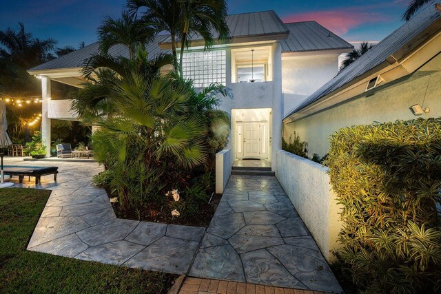 exterior entry at dusk featuring a patio area