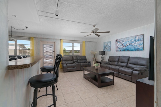 living room featuring light tile patterned floors, a textured ceiling, and ceiling fan