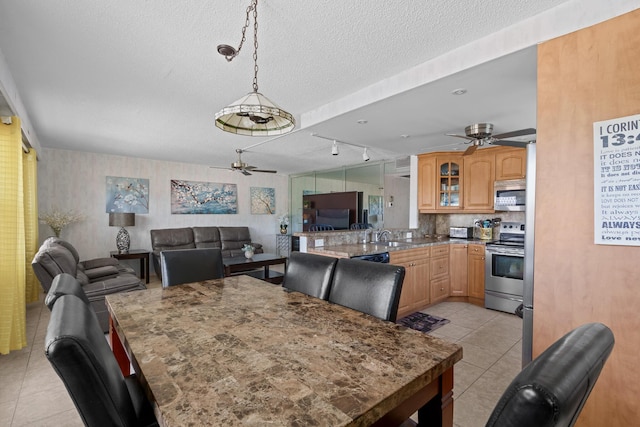 dining space with light tile patterned floors, a textured ceiling, sink, and ceiling fan