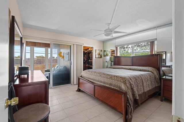 tiled bedroom with multiple windows, a spacious closet, access to outside, and a textured ceiling