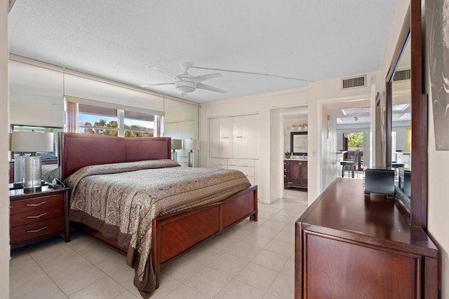 tiled bedroom with ceiling fan, ensuite bath, and a textured ceiling