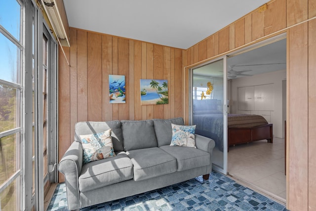 living room featuring ceiling fan, wooden walls, and dark tile patterned floors