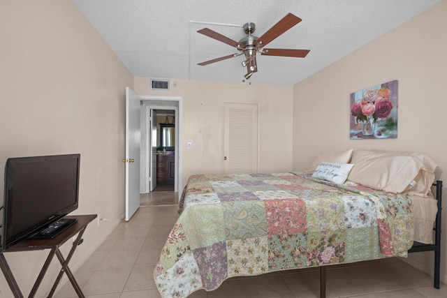 bedroom featuring light tile patterned flooring, ceiling fan, a textured ceiling, and a closet