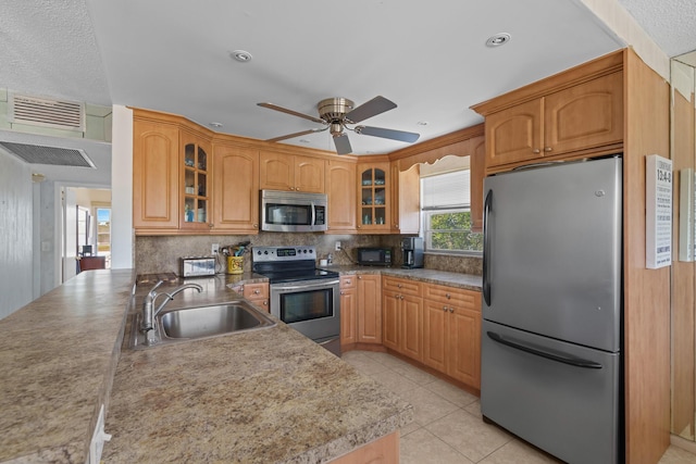 kitchen featuring light tile patterned flooring, appliances with stainless steel finishes, sink, decorative backsplash, and ceiling fan