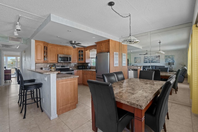 kitchen featuring a kitchen bar, hanging light fixtures, kitchen peninsula, ceiling fan, and stainless steel appliances