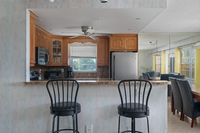 kitchen with tasteful backsplash, stainless steel appliances, a breakfast bar, and kitchen peninsula