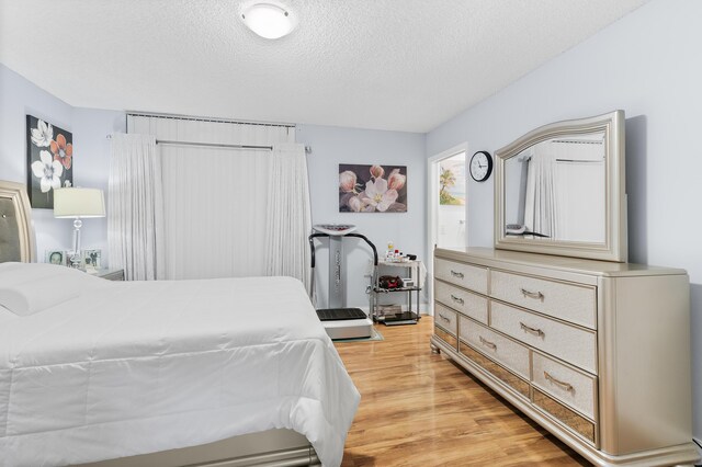 bedroom featuring a textured ceiling and light hardwood / wood-style flooring