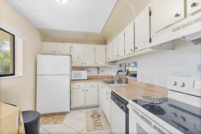 kitchen with light tile patterned flooring, white cabinetry, sink, decorative backsplash, and white appliances