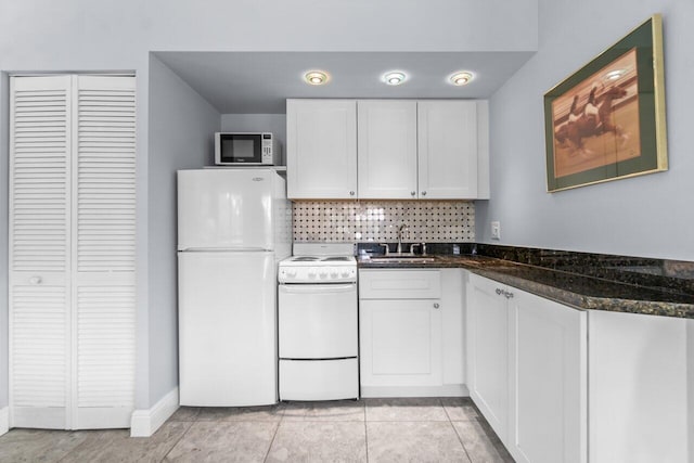 kitchen with sink, tasteful backsplash, dark stone countertops, white appliances, and white cabinets