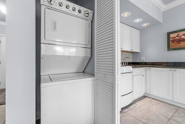 washroom with light tile patterned floors, crown molding, and stacked washer / dryer