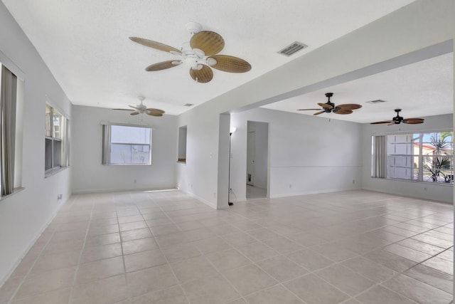 tiled empty room featuring a textured ceiling