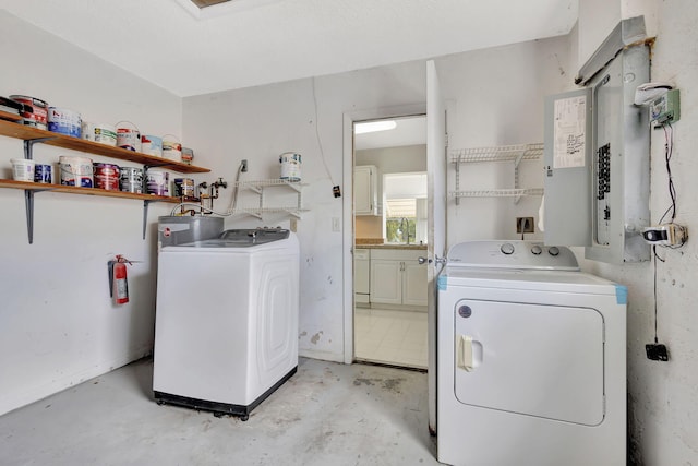 clothes washing area featuring water heater, sink, electric panel, and independent washer and dryer