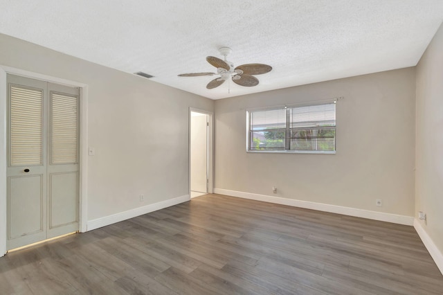 empty room featuring ceiling fan, dark hardwood / wood-style floors, and a textured ceiling