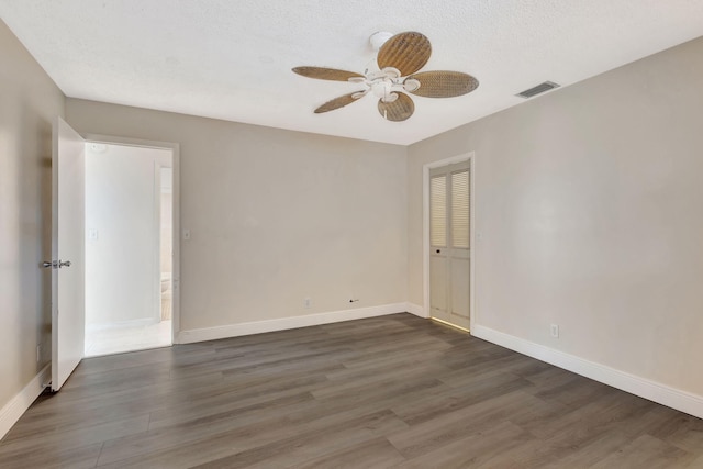 unfurnished room featuring dark wood-type flooring, a textured ceiling, and ceiling fan