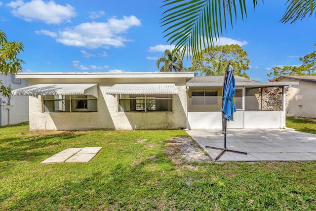 back of property with a lawn, a sunroom, and a patio