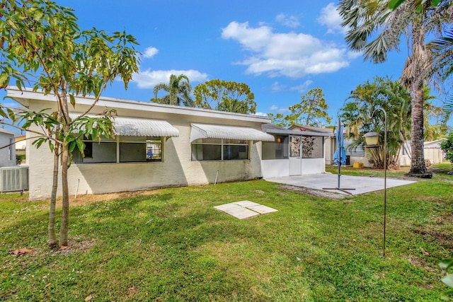 back of house featuring a sunroom, a patio area, a lawn, and central air condition unit