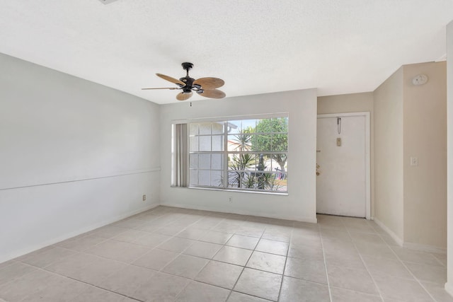 spare room featuring a textured ceiling, ceiling fan, and light tile patterned flooring