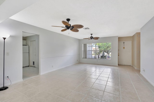 tiled empty room featuring ceiling fan and a textured ceiling