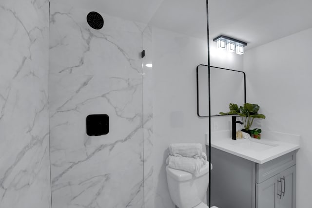 bathroom with vanity, tiled shower, and toilet