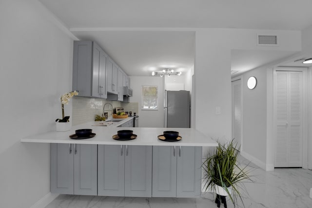 kitchen featuring sink, gray cabinets, stainless steel appliances, and kitchen peninsula