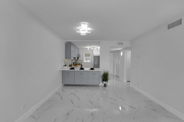 kitchen featuring sink, kitchen peninsula, and stainless steel refrigerator