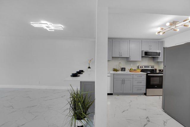 kitchen featuring stainless steel appliances, sink, gray cabinetry, and backsplash