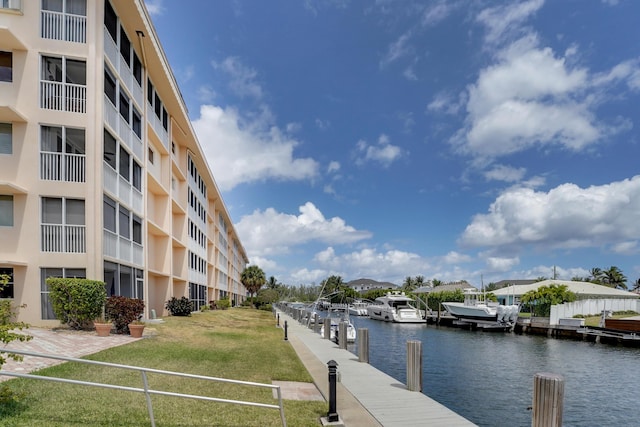 view of dock with a lawn and a water view