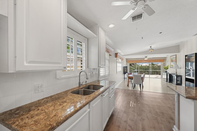 kitchen with white cabinetry, sink, decorative backsplash, and dark stone countertops