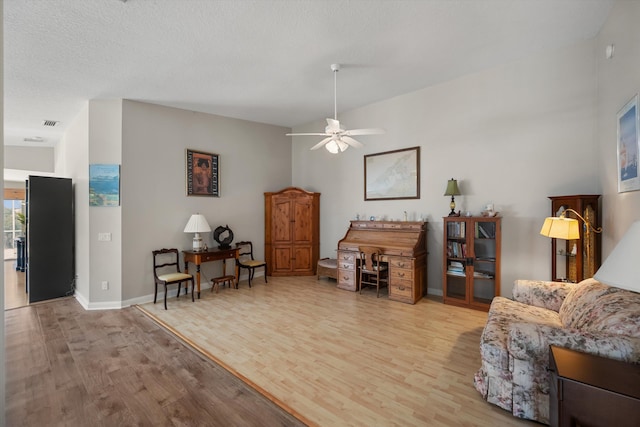 living room featuring a textured ceiling, light hardwood / wood-style flooring, and ceiling fan