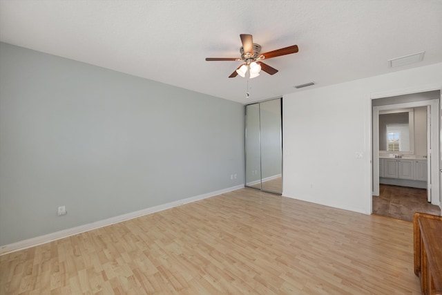 unfurnished bedroom with ceiling fan, light hardwood / wood-style floors, a closet, and a textured ceiling