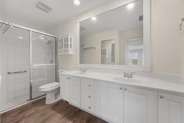 bathroom featuring vanity, hardwood / wood-style floors, a shower with shower door, and toilet