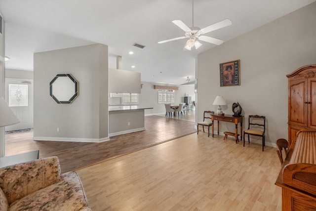 living room with light hardwood / wood-style flooring, ceiling fan, and vaulted ceiling