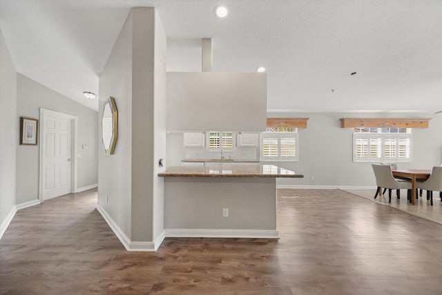 kitchen featuring lofted ceiling, light stone counters, a textured ceiling, dark hardwood / wood-style flooring, and white cabinets