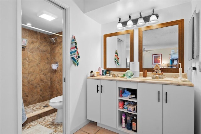 bathroom featuring tiled shower, tile patterned floors, toilet, vanity, and ceiling fan