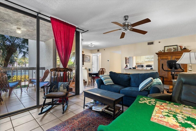 tiled living room with ceiling fan, plenty of natural light, a textured ceiling, and a wall of windows