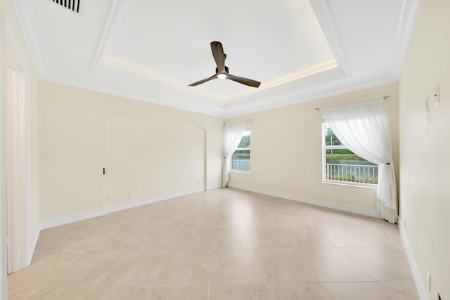 tiled spare room featuring ceiling fan, ornamental molding, plenty of natural light, and a tray ceiling