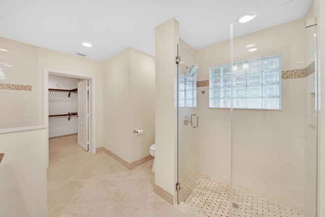 bathroom with a shower with shower door, tile patterned floors, and toilet