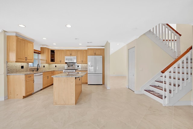 kitchen featuring light stone counters, backsplash, white appliances, and a center island