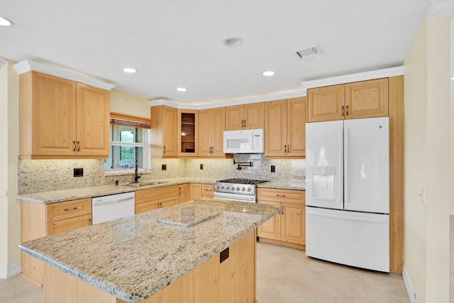 kitchen with sink, tasteful backsplash, a center island, white appliances, and light stone countertops