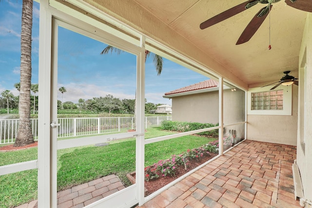 unfurnished sunroom with ceiling fan