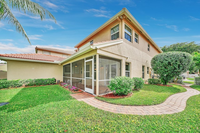 rear view of property featuring a sunroom and a yard