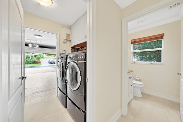 washroom with plenty of natural light, cabinets, washing machine and clothes dryer, and light tile patterned flooring