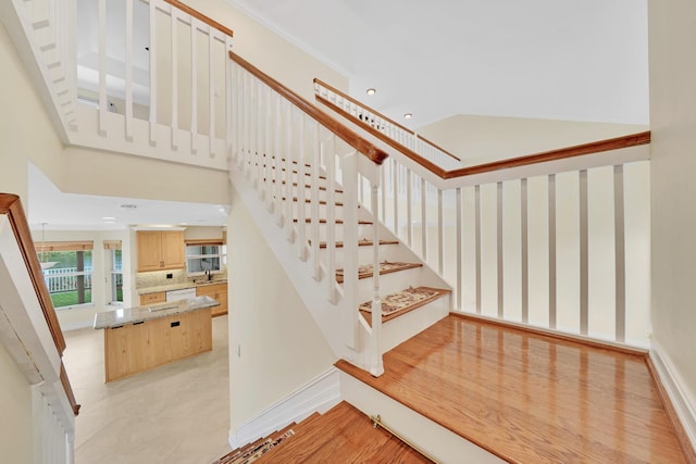 stairway featuring sink, crown molding, and a high ceiling